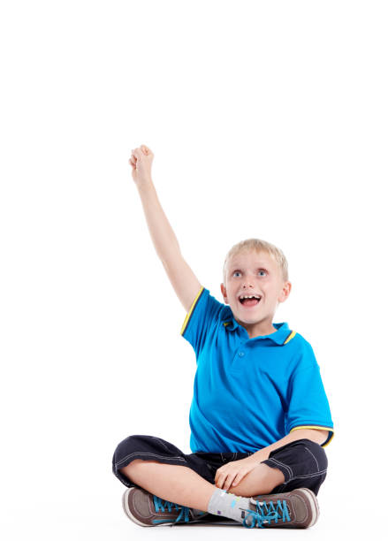 istock Little blond boy sits, raising hand to answer or volunteer 1080670984