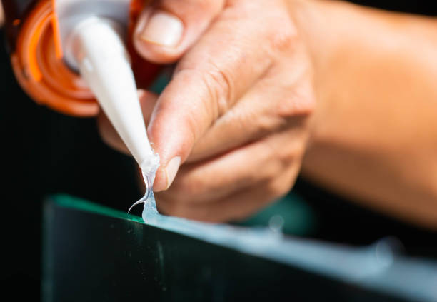 herren hand nutzt silikonkleber mit klebstoff um den spiegel mit aluminium verbinden. - silikon stock-fotos und bilder