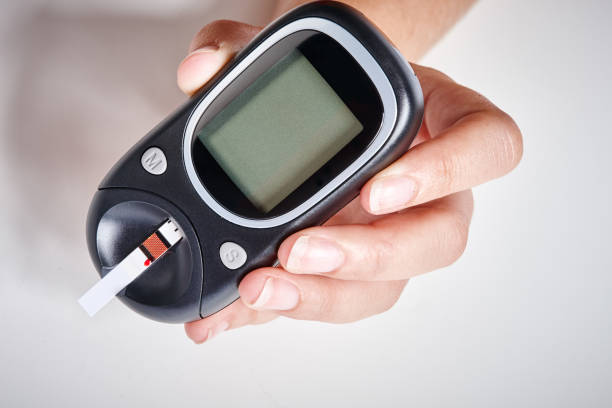 рука проведения глаукометр для измерения уровня сахара в крови у диабетиков - diabetes glaucometer healthcare and medicine close up стоковые фото и изображения