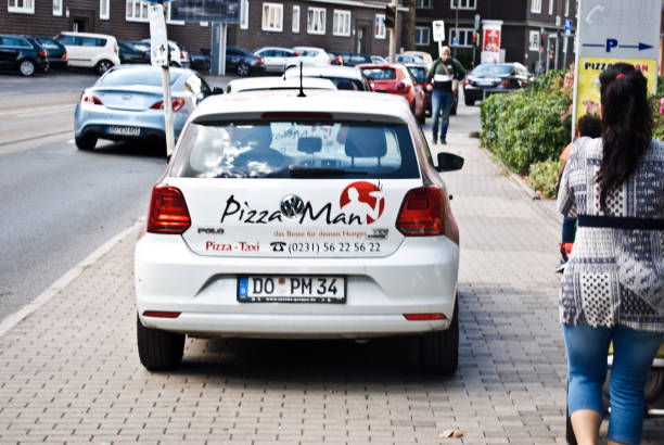 пешеходы, проходя мимо пиццерии (pizza man) автомобиль доставки припаркован на тротуаре в дортмунде - германия - franchising concepts brand name road sign стоковые фото и изображения