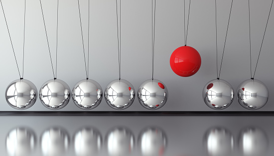 A red colored hanging sphere standing out from the chrome ones. ( 3d render )