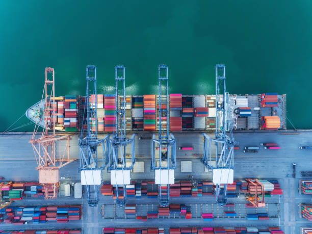istock Aerial top view container ship at sea port and working crane bridge loading container for import export, shipping or transportation concept background. 1080699874