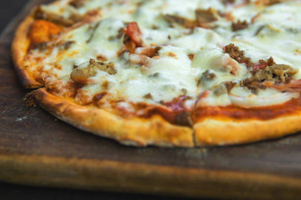 Delicious pizza with mozzarella cheese, minced meat and bacon on wooden board