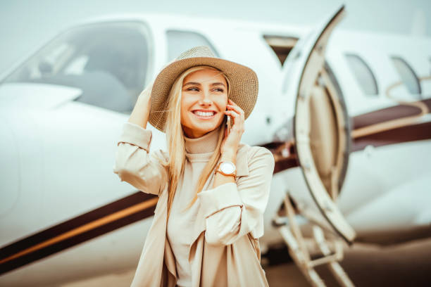 istock Rich young woman talking on her mobile phone while walking next to a private jet parked on an airport tarmac 1080723726