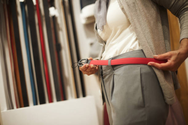 femme méconnaissable essayer une ceinture en cuir rouge dans un magasin de sacs et accessoires - belt leather fashion women photos et images de collection