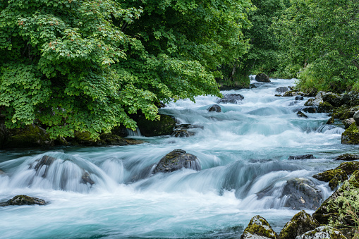 Beautiful river at Geiranger in Norway with turquoise flowing water and lush green surrounding trees