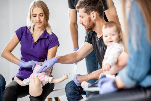 Group of people during the first aid training for baby Group of people during the first aid training with instructor showing on manikin how to do artificial respiration for the baby cpr stock pictures, royalty-free photos & images