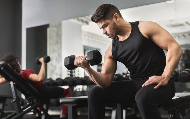 arabe homme musclé faisant des séances d’entraînement de biceps en gym - crouching male men sensuality photos et images de collection