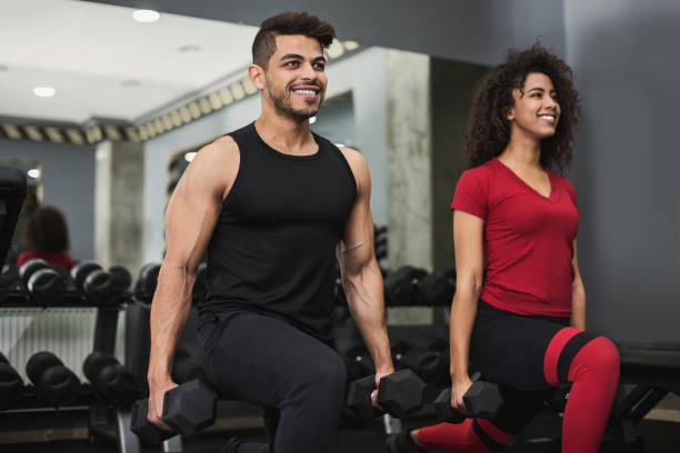 formation de couple diversifiée avec des haltères dans la salle de gym - men weight training african descent male photos et images de collection