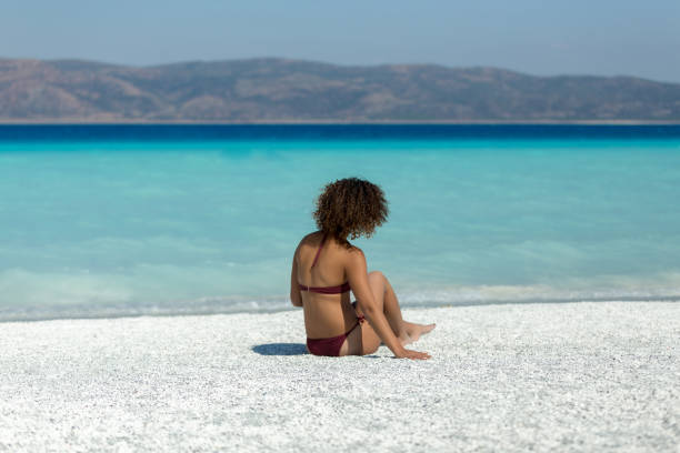 istock Beautiful woman sitting on sand 1080746840