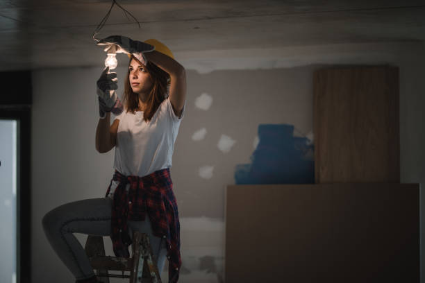 eletricista feminina lâmpada de aperto durante o processo de renovação em casa. - changing lightbulb - fotografias e filmes do acervo