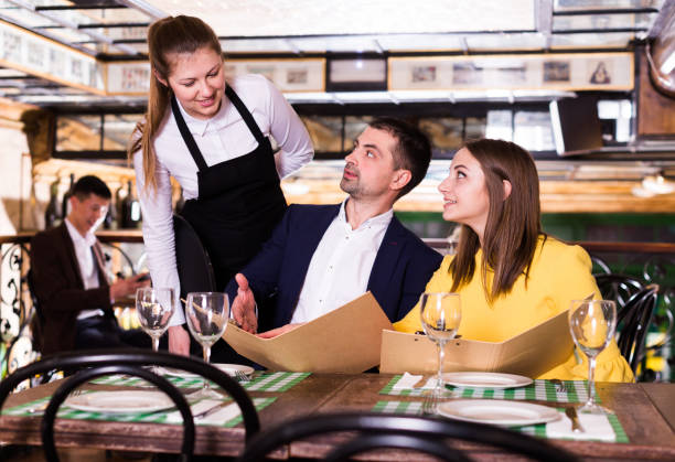 istock Female waiter is taking order from smiling couple with menu who is dinning 1080783802