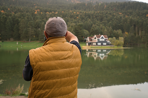 Photographer senior man hiking on the coast of a lake