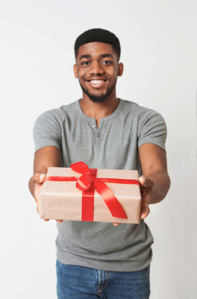 istock Black man holding gift in white box wrapped with red ribbon and bow 1080802116