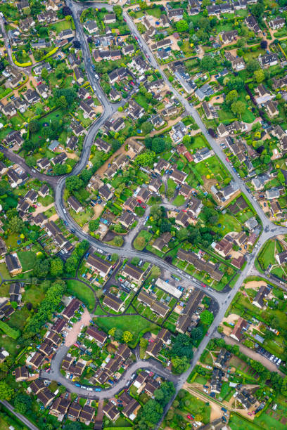 Aerial photograph of family homes suburban housing development green gardens Aerial view onto the roads and rooftops of this tranquil suburban scene with neatly tended gardens, cars parked on driveways and vibrant green summer foliage. aircraft point of view stock pictures, royalty-free photos & images