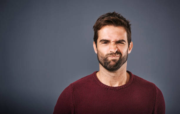 Mmm...nah! Studio shot of a handsome young man looking skeptical against a gray background grimacing stock pictures, royalty-free photos & images