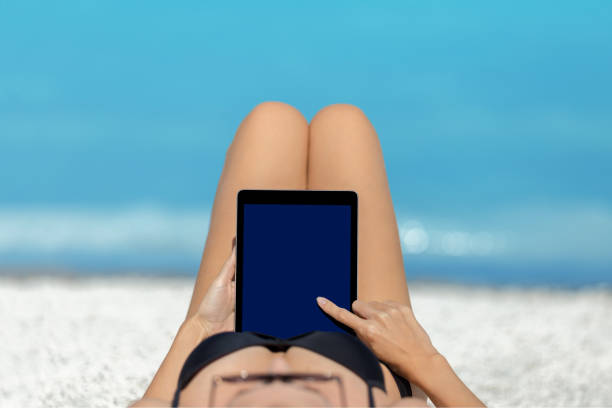 istock Woman lying on the beach enjoying with tablet 1080815568