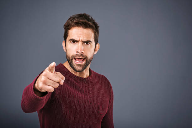 I warned you that would happen! Studio shot of a handsome young man pointing a finger in anger against a gray background anger stock pictures, royalty-free photos & images