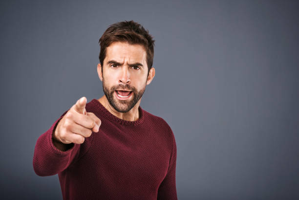 I warned you that would happen! Studio shot of a handsome young man pointing a finger in anger against a gray background furious stock pictures, royalty-free photos & images