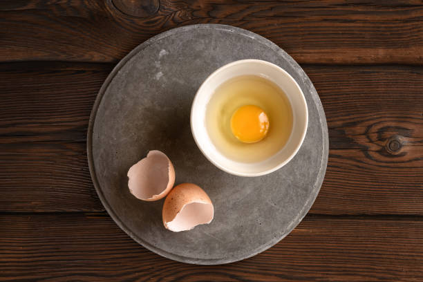 istock plate with raw broken egg, shell on concrete slab, on dark background 1080832490