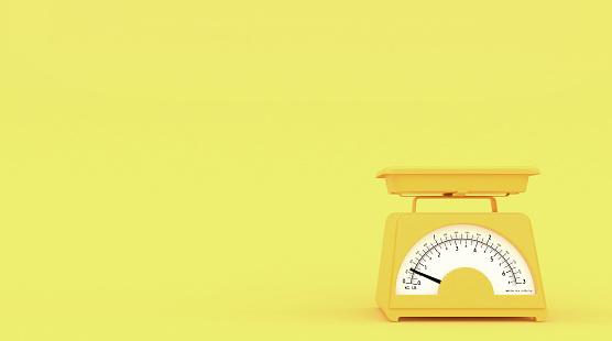 Yellow old kitchen weight scales on yellow background with free space for text or logo.