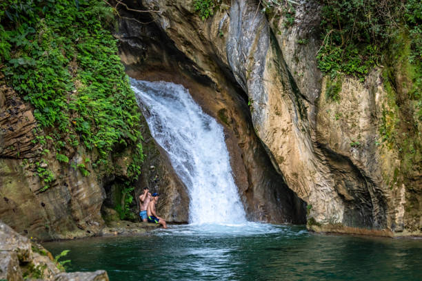 Young woman relaxes in pool below waterfall, Soca River