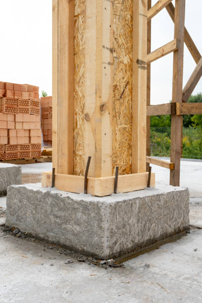 istock Brick house construction concept. Close up vertical photo of building support element with wooden column and concrete formwork against red brick wall 1080854800