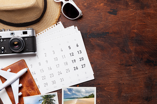 Travel vacation background concept with calendar, sun hat, camera, passport, airplane toy and weekend photos on wooden backdrop. Top view with copy space. Flat lay. All photos taken by me