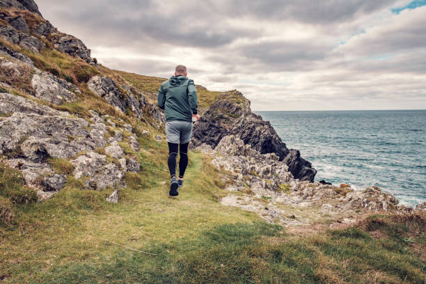 Man trail running along the rugged Cornish coastline on an Autumn day.
