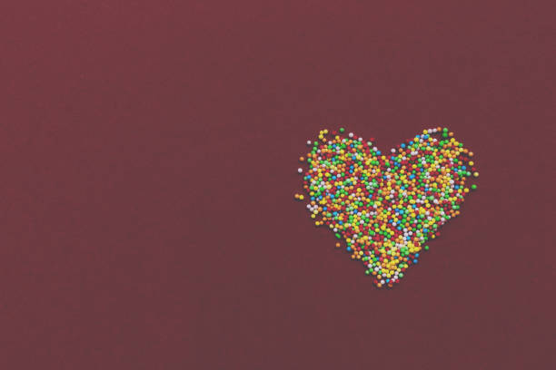 istock Rainbow sprinkles heart on red background. Toned. 1080876098