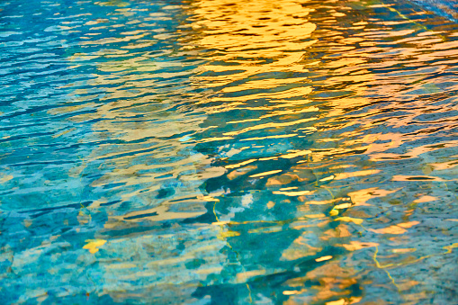 Blue pool transparent water with sun reflections