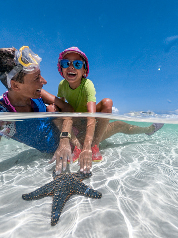 Mother and Daughter Enjoying Stroking a Starfish Together in Indian Ocean.