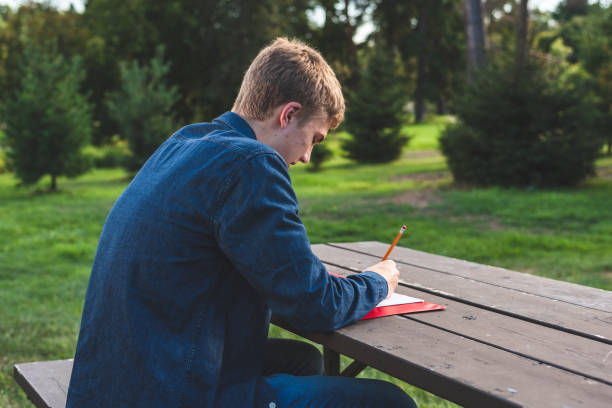 istock Teenager doing his homework alone in a park. 1080888410