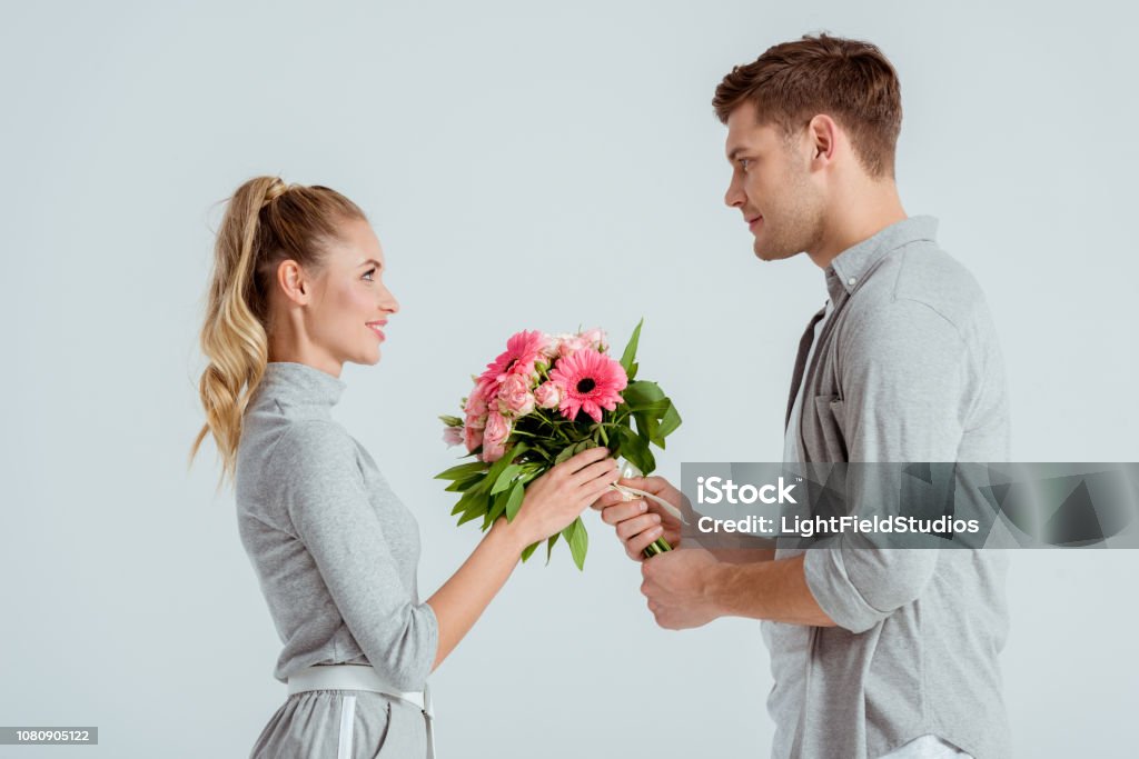 Hombre Guapo Dando Ramo De Flores Color Rosa A La Mujer Aislada En Gris Foto de stock y más banco de imágenes de Adulto - iStock Hombre Guapo Dando Ramo De Flores Color Rosa A La Mujer Aislada En Gris Foto de stock y más banco de imágenes de Adulto - iStock