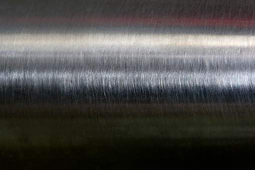 Texture of reflection on stainless steel pipe in dark room, abstract background