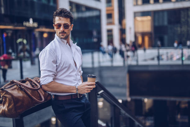 giovane uomo d'affari elegante con caffè da asporto - abbigliamento elegante foto e immagini stock