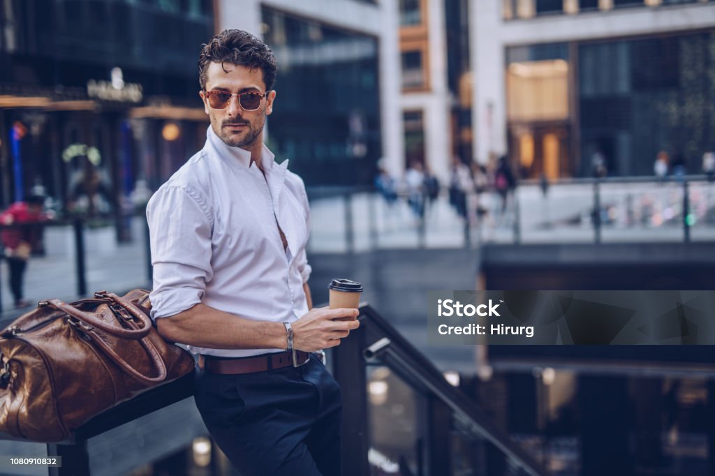 Young stylish businessman having takeaway coffee One young handsome businessman drinking takeaway coffee on the street Men Stock Photo