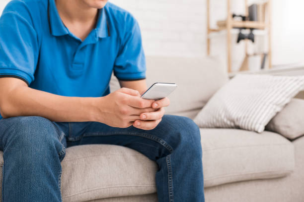 guy using smartphone while sitting on sofa - hipster people surfing the net internet imagens e fotografias de stock