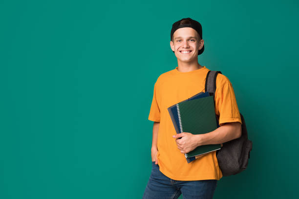 Teen guy with books and backpack over background Teen guy with books and backpack standing over turquoise background with copy space male likeness stock pictures, royalty-free photos & images