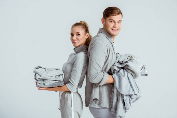 istock smiling couple looking at camera and holding grey clothes isolated on grey 1080930634