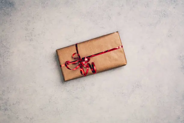Gift or present in brown paper box with red ribbon, above view. Top centered closeup view with copy space.