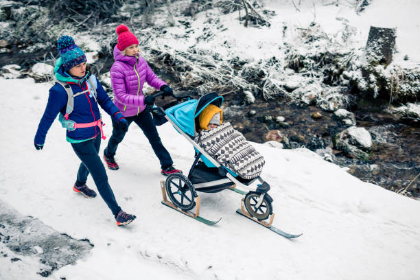 две женщины с детской коляской наслаждаются зимой в лесу, семейное время - tatra mountains healthy lifestyle leisure activity mountain стоковые фото и изображения