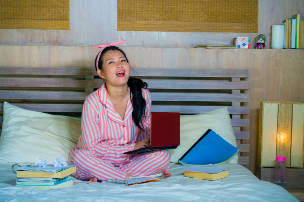 mujer adolescente joven lindo y feliz nerd asiático japonés estudiante nerd gafas y pelo de la cinta de estudiando en casa habitación sentado en cama con ordenador portátil y libros de texto sonriendo seguro - nerd student female exam fotografías e imágenes de stock