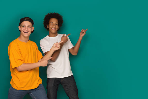 istock Two happy friends pointing fingers away at copy space 1080967282