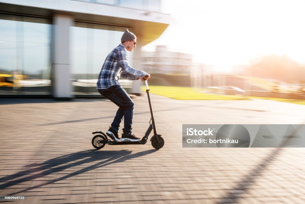Giovane su scooter elettrico in strada - Foto stock royalty-free di Monopattino
