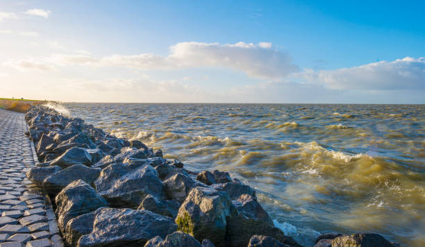 Dike along a stormy lake in sunlight at fall stock photo