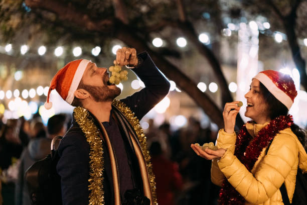 Christmas in Spain Happy couple celebrating New Year outside at night and eating grapes traditional christmas stock pictures, royalty-free photos & images