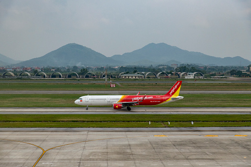 A VietJet Air Airbus A321 just landed at Hanoi International Airport during a cloudy morning.