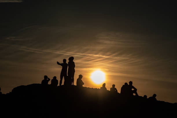 istock Silhouettes of people standing and sitting on a hill while watching sunset 1081003180