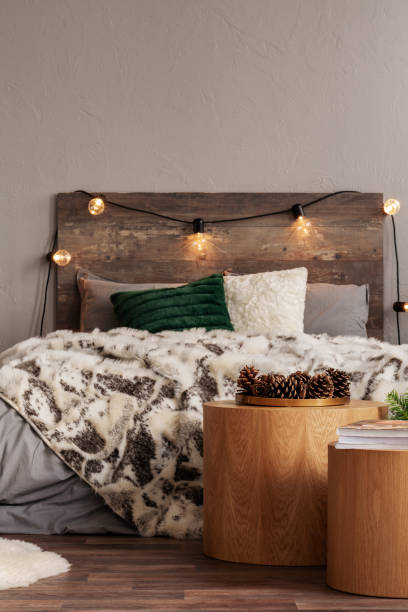 istock Cones on round wooden table in warm bedroom interior with king size bed with light bulbs on headboard 1081004164